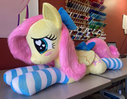Size: 2336x1814 | Tagged: safe, artist:qtpony, fluttershy (mlp), equine, fictional species, mammal, pegasus, pony, feral, friendship is magic, hasbro, my little pony, 2023, blushing, bow, clothes, cute, eyelashes, female, folded wings, hair bow, heart, heart eyes, high res, irl, legwear, lying down, mare, photo, plushie, prone, quadrupedal, smiling, socks, solo, solo female, striped clothes, striped legwear, toy, wingding eyes, wings
